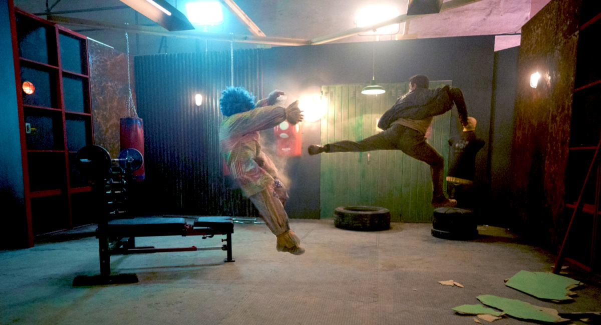 Beau Fowler as Paco The Killer Clown and Scott Adkins as Mike Fallon in the action/thriller film, 'Accident Man: Hitman's Holiday.'