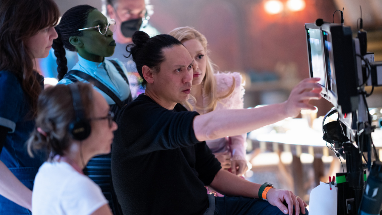 (Center L to R) Cynthia Erivo (as Elphaba), Director Jon M. Chu, and Ariana Granda (as Glinda) on the set of 'Wicked'. Photo: Universal Pictures.