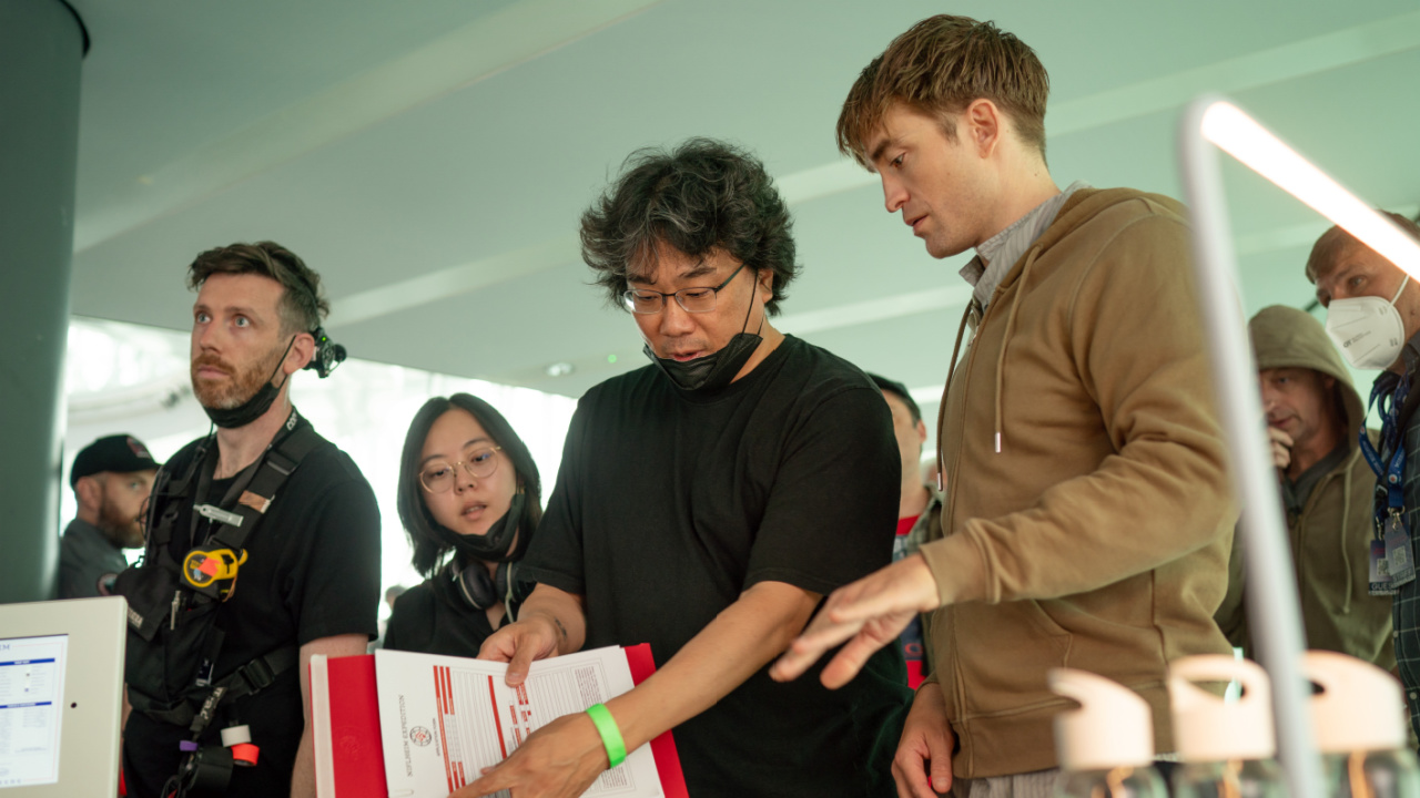 (L to R) Sutradara Bong Joon Ho dan Robert Pattinson di lokasi syuting 'Mickey 17,' rilis gambar Warner Bros. Kredit Foto: Jonathan Olley.