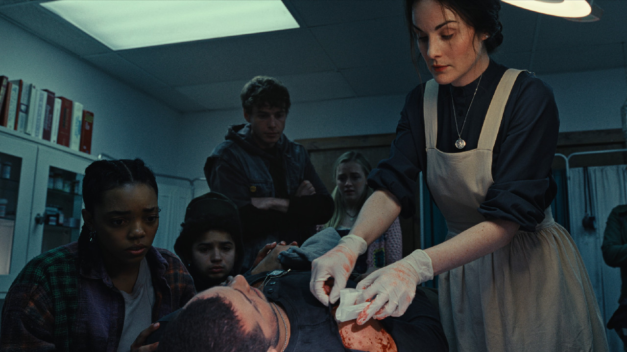 (L to R) Vicky (Regan Aliyah) watches as Ben receives treatment from Clara (Michelle Dockery) in 'Please Don't Feed the Children.' Photo: Tubi.