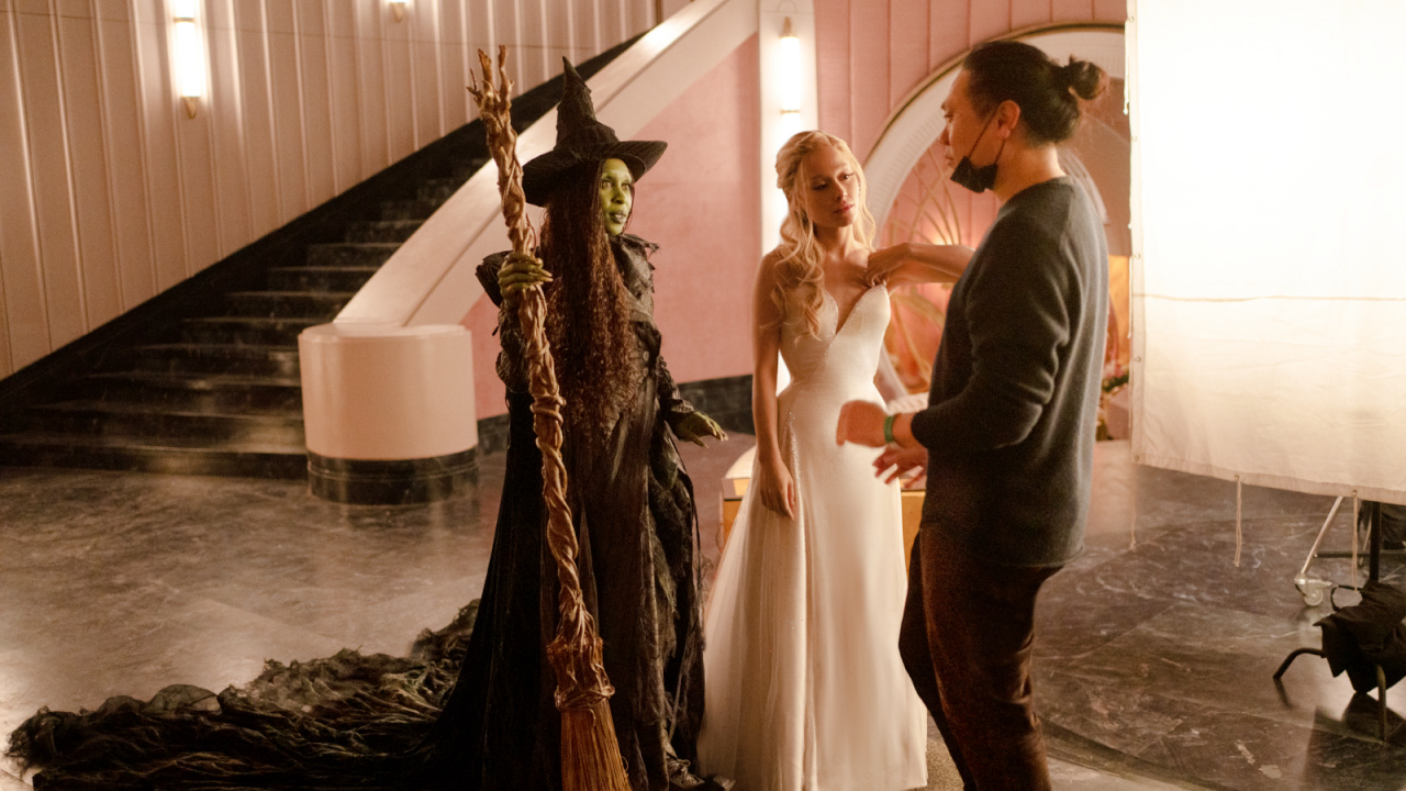 (L to R) Cynthia Erivo (as Elphaba), Ariana Grande (as Glinda), and Director Jon M. Chu on the set of 'Wicked For Good'.